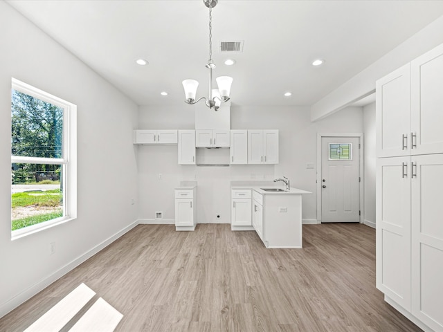 kitchen with sink, light hardwood / wood-style floors, white cabinets, decorative light fixtures, and a chandelier