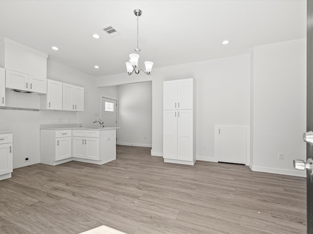 kitchen featuring white cabinetry, hanging light fixtures, light hardwood / wood-style flooring, and a chandelier