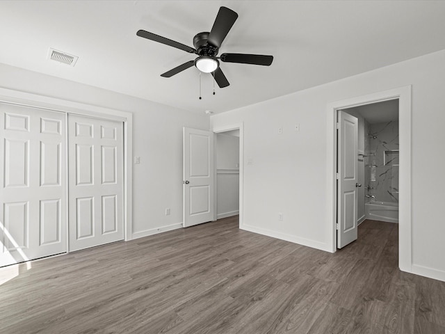 unfurnished bedroom with ceiling fan, ensuite bath, dark hardwood / wood-style floors, and a closet