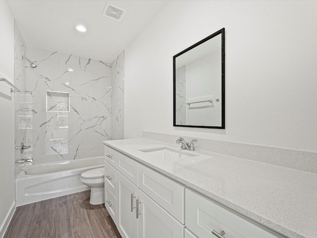 full bathroom featuring hardwood / wood-style flooring, tiled shower / bath, vanity, and toilet