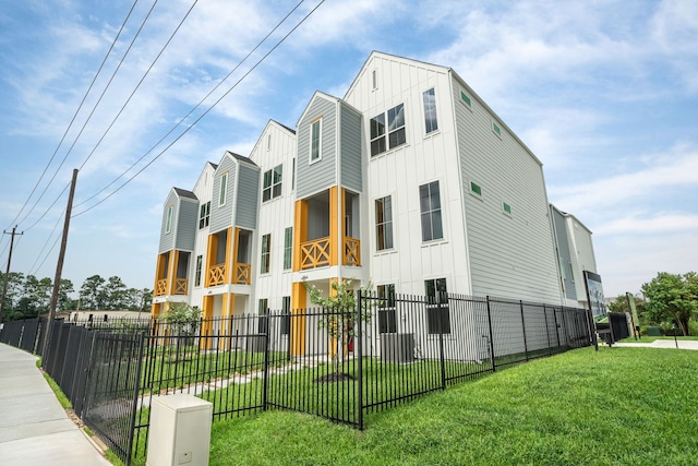 view of property exterior with board and batten siding, a lawn, and fence