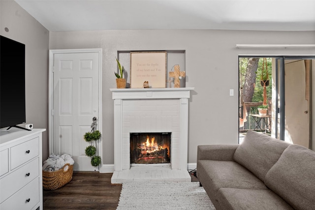 living room with a brick fireplace and dark hardwood / wood-style floors