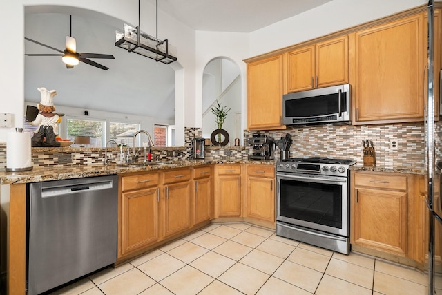 kitchen featuring stone counters, appliances with stainless steel finishes, sink, backsplash, and ceiling fan