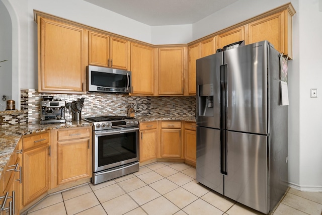 kitchen with stainless steel appliances, tasteful backsplash, light tile patterned floors, and light stone counters