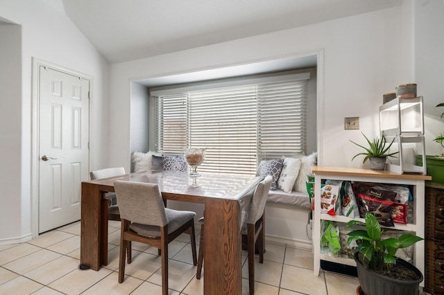 dining area with light tile patterned floors and vaulted ceiling