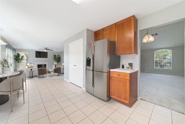 kitchen with pendant lighting, light tile patterned floors, ceiling fan with notable chandelier, and stainless steel fridge