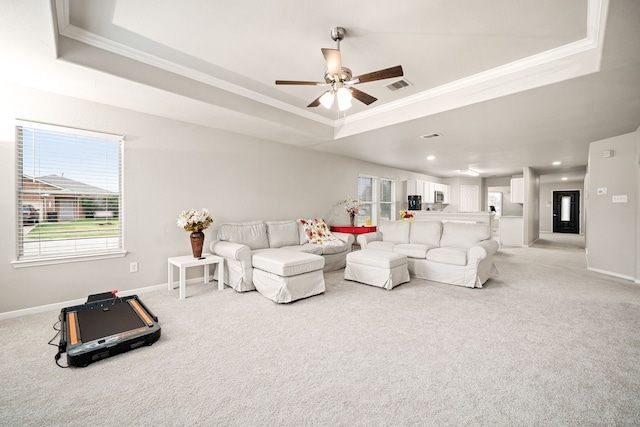 carpeted living room with crown molding, a healthy amount of sunlight, and a tray ceiling