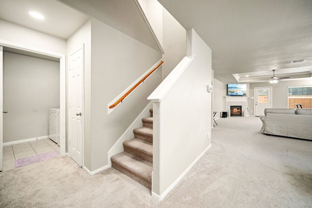 stairway with ceiling fan, carpet flooring, a fireplace, and washer and clothes dryer