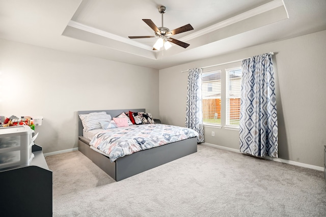 bedroom featuring a tray ceiling, ornamental molding, light colored carpet, and ceiling fan