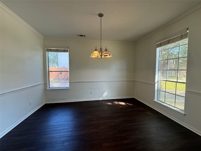 spare room featuring dark hardwood / wood-style flooring, crown molding, a textured ceiling, and an inviting chandelier