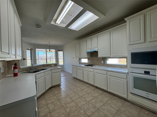 kitchen featuring pendant lighting, sink, white appliances, tasteful backsplash, and white cabinets