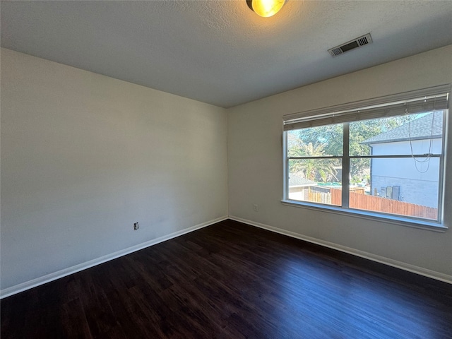 unfurnished room featuring dark wood-type flooring and a textured ceiling