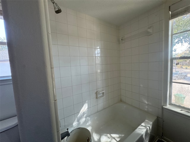 bathroom with toilet and tiled shower / bath