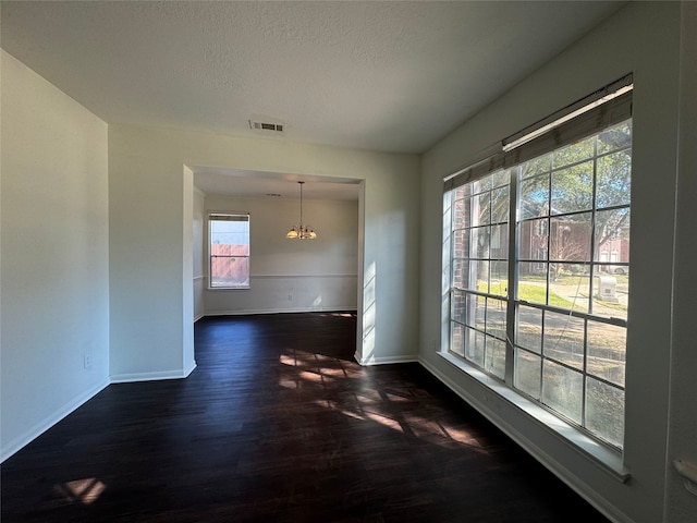 interior space featuring dark hardwood / wood-style flooring, a textured ceiling, and a notable chandelier