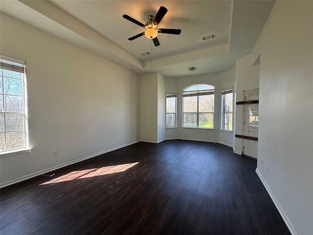 unfurnished living room with a raised ceiling, dark hardwood / wood-style floors, and ceiling fan