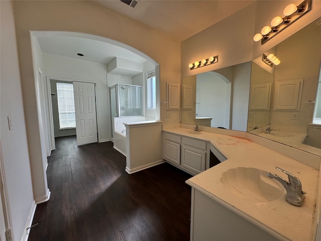 bathroom with hardwood / wood-style flooring, vanity, and plus walk in shower