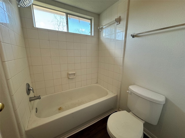 bathroom with toilet and tiled shower / bath combo