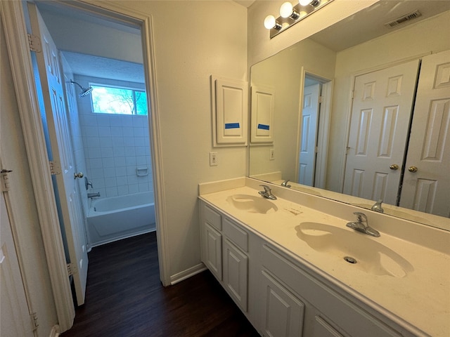 bathroom with wood-type flooring, vanity, and tiled shower / bath