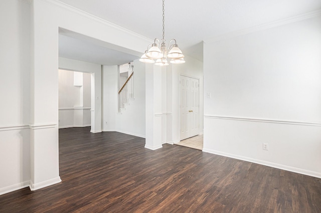 spare room featuring stairway, dark wood-type flooring, ornamental molding, a chandelier, and baseboards