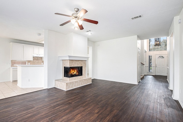 unfurnished living room with visible vents, a fireplace, light wood-style flooring, and ceiling fan