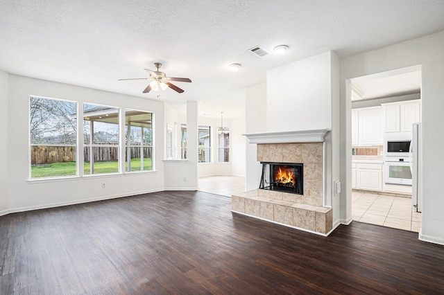 unfurnished living room featuring light wood finished floors, a wealth of natural light, a fireplace, and visible vents