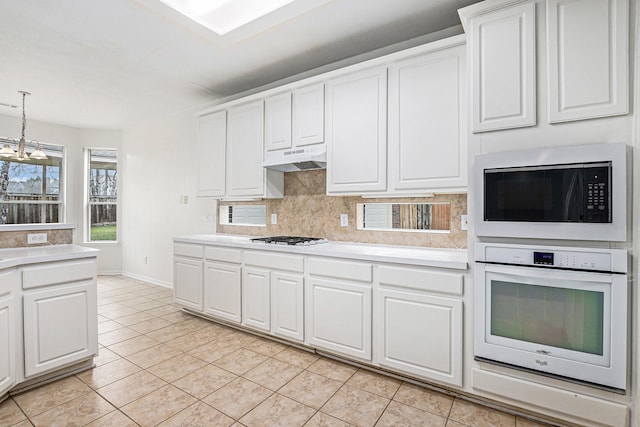 kitchen with light countertops, white appliances, white cabinetry, and under cabinet range hood