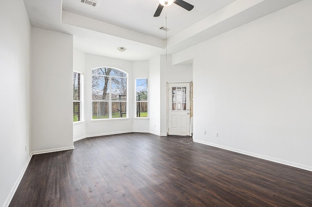 unfurnished room featuring baseboards, a raised ceiling, and dark wood-type flooring