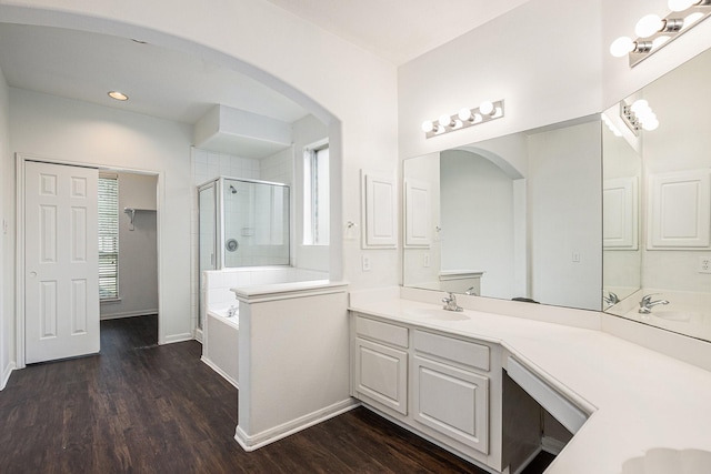 bathroom featuring a garden tub, a shower stall, vanity, wood finished floors, and baseboards