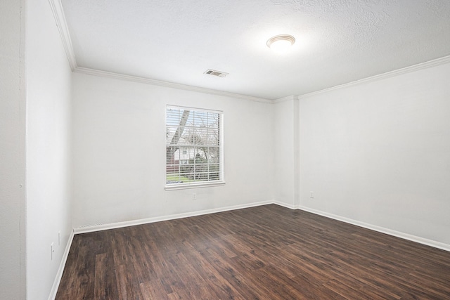 spare room featuring dark wood-type flooring, visible vents, crown molding, and baseboards