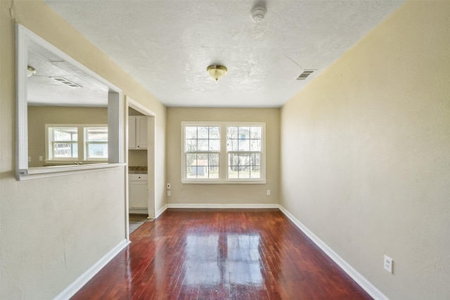 empty room featuring dark wood-type flooring and a textured ceiling