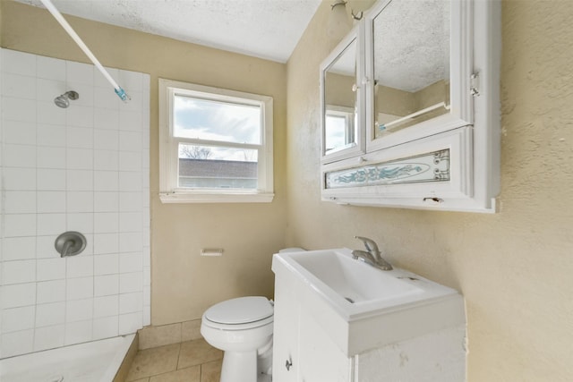 bathroom with vanity, tiled shower, toilet, tile patterned floors, and a textured ceiling