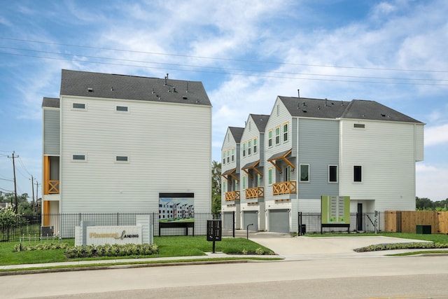 view of building exterior with driveway, an attached garage, and fence