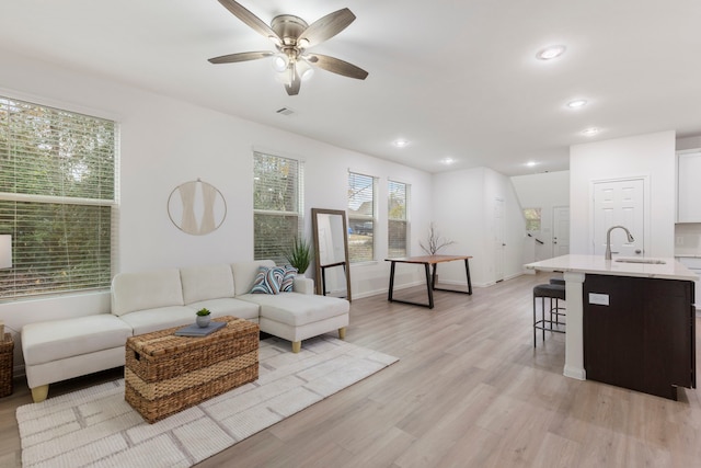 living room featuring sink, light hardwood / wood-style flooring, and ceiling fan