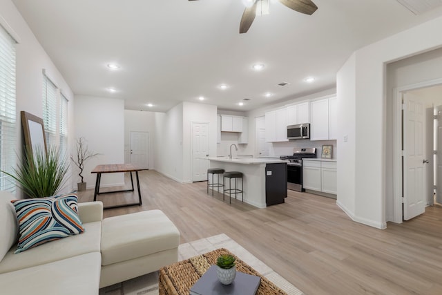 living room featuring sink, ceiling fan, and light hardwood / wood-style flooring