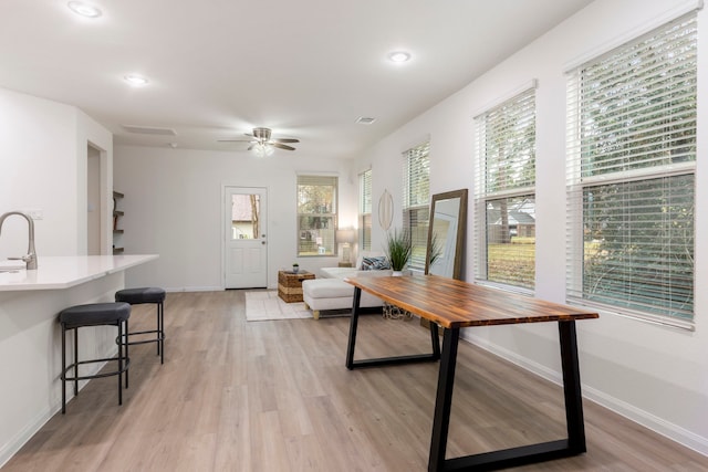 dining room with ceiling fan, sink, and light wood-type flooring