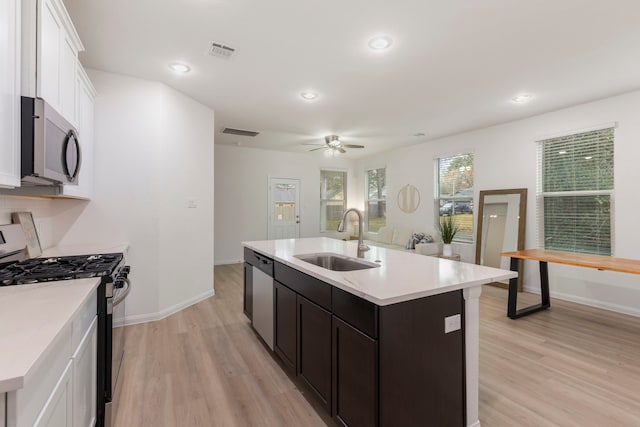 kitchen featuring appliances with stainless steel finishes, white cabinetry, an island with sink, sink, and light hardwood / wood-style floors