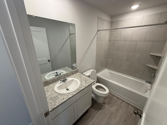 full bathroom featuring hardwood / wood-style flooring, vanity, toilet, and tiled shower / bath