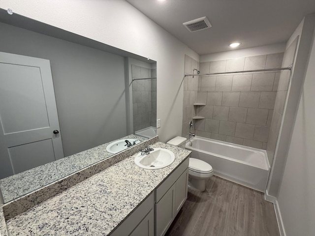 full bathroom featuring tiled shower / bath, vanity, toilet, and hardwood / wood-style floors