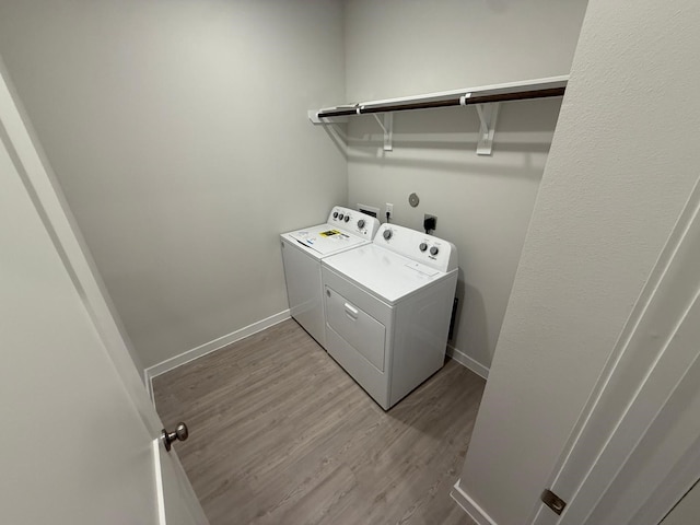 laundry area with washing machine and clothes dryer and light hardwood / wood-style flooring