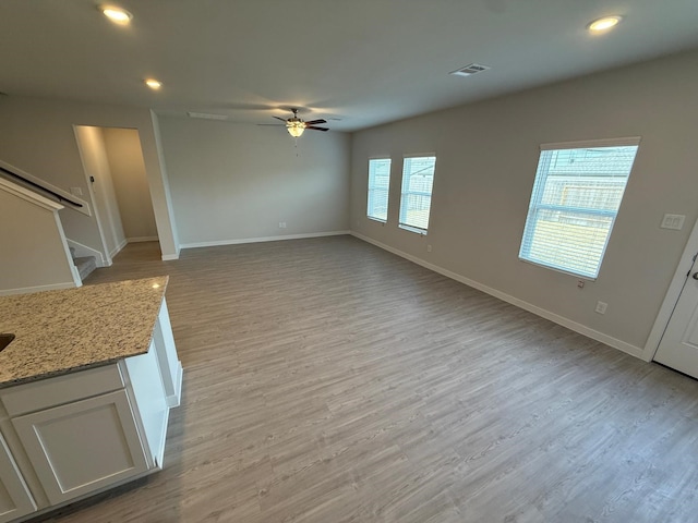 unfurnished living room featuring ceiling fan and light wood-type flooring