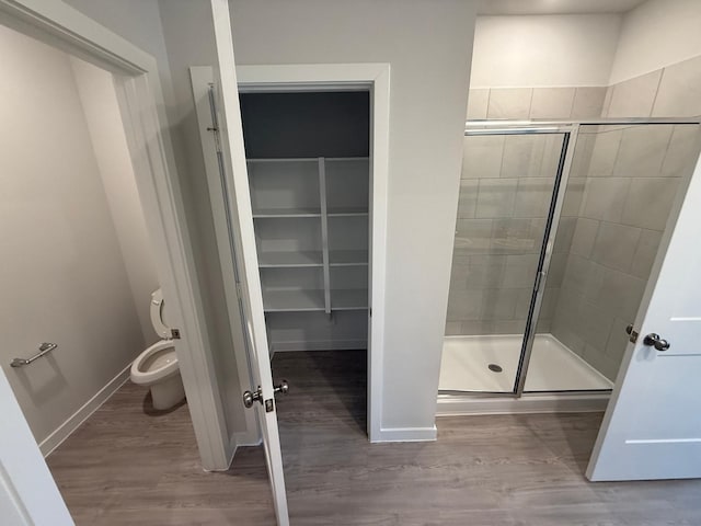 bathroom with hardwood / wood-style flooring, toilet, and an enclosed shower