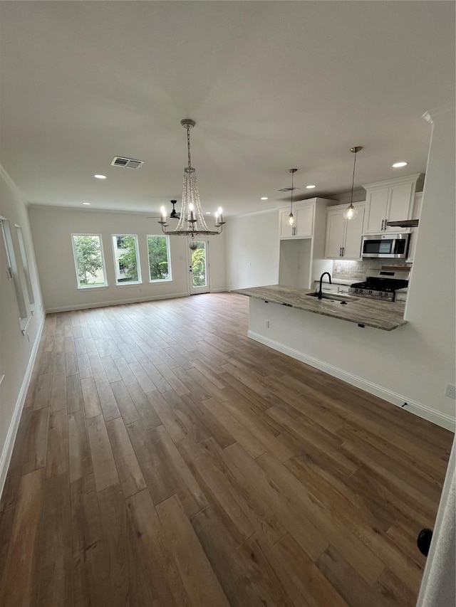 unfurnished living room with white cabinetry, dark hardwood / wood-style floors, hanging light fixtures, and a notable chandelier