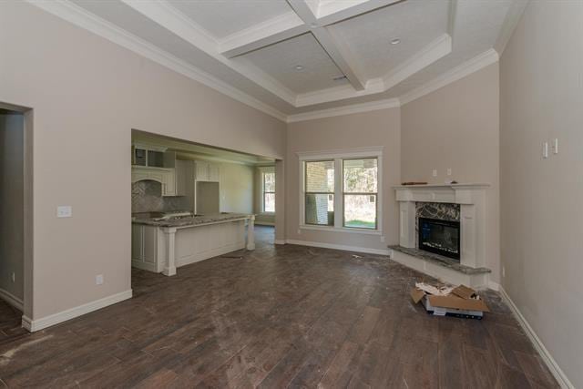 unfurnished living room with dark wood-type flooring, coffered ceiling, ornamental molding, a fireplace, and a high ceiling