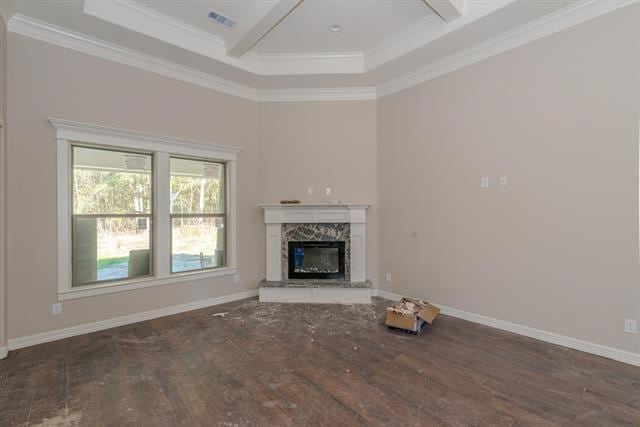 unfurnished living room with dark wood-type flooring, a premium fireplace, crown molding, and a tray ceiling