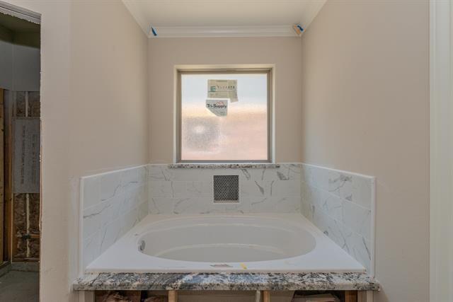 bathroom featuring a relaxing tiled tub and crown molding