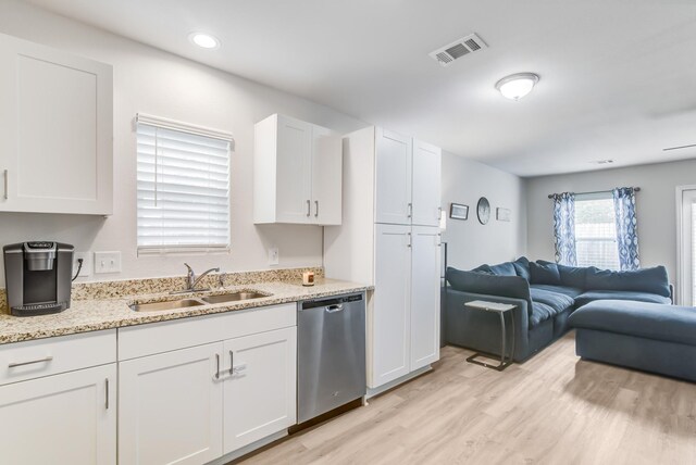 kitchen with sink, white cabinetry, stainless steel dishwasher, light stone countertops, and light hardwood / wood-style floors