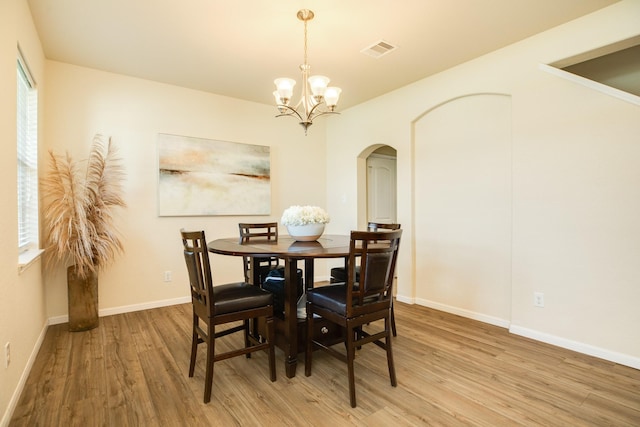 dining space with a healthy amount of sunlight, wood-type flooring, and a chandelier