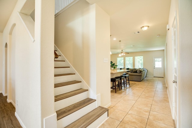 staircase featuring tile patterned floors and ceiling fan