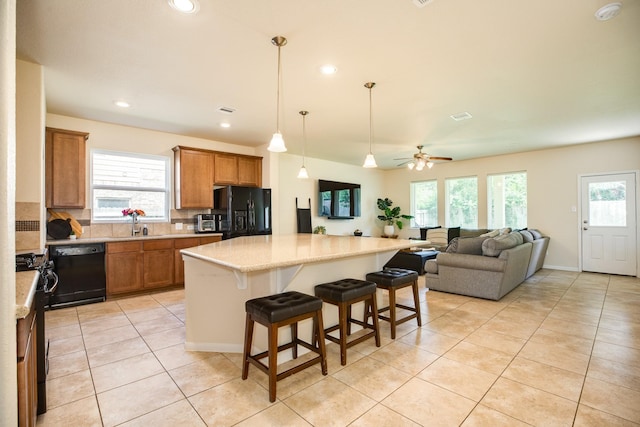 kitchen featuring a kitchen breakfast bar, a wealth of natural light, a kitchen island, and black appliances