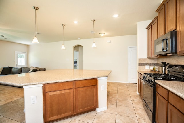 kitchen featuring light tile patterned flooring, a kitchen island, tasteful backsplash, hanging light fixtures, and black appliances